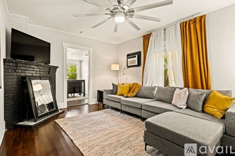 A living room with a grey couch and a fireplace.