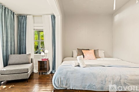 A bedroom with a large bed and a chair.