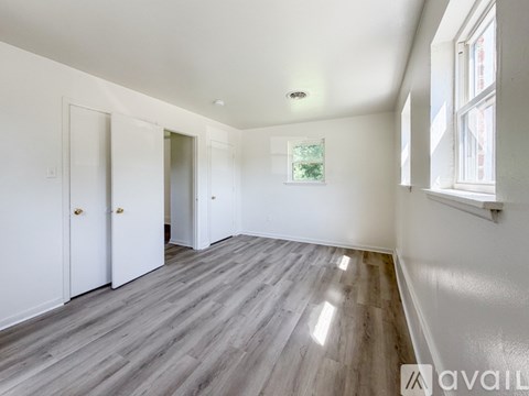 A spacious room with wooden flooring and white walls.