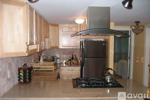 A kitchen with wooden cabinets and a stainless steel refrigerator.