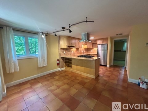 A kitchen with a tile floor and a window with curtains.