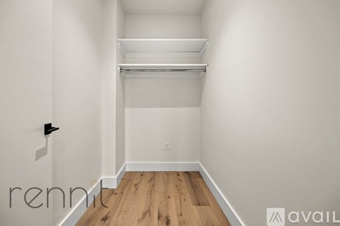 A white room with a slanted ceiling and a wooden floor.