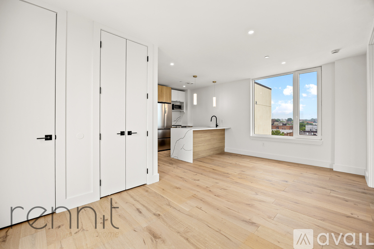 A room with white cupboards and a window overlooking a building.