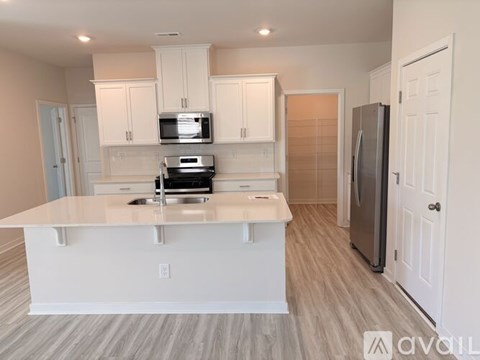 A kitchen with white cabinets and a wooden floor.