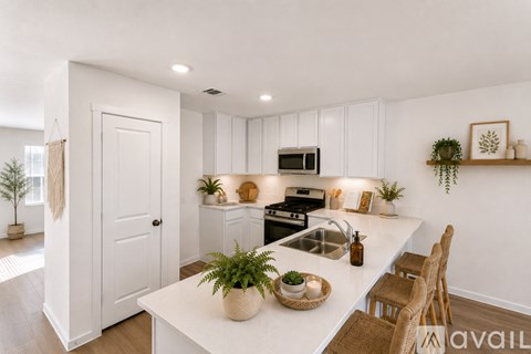 A kitchen with white cabinets and a white island with a plant on it.