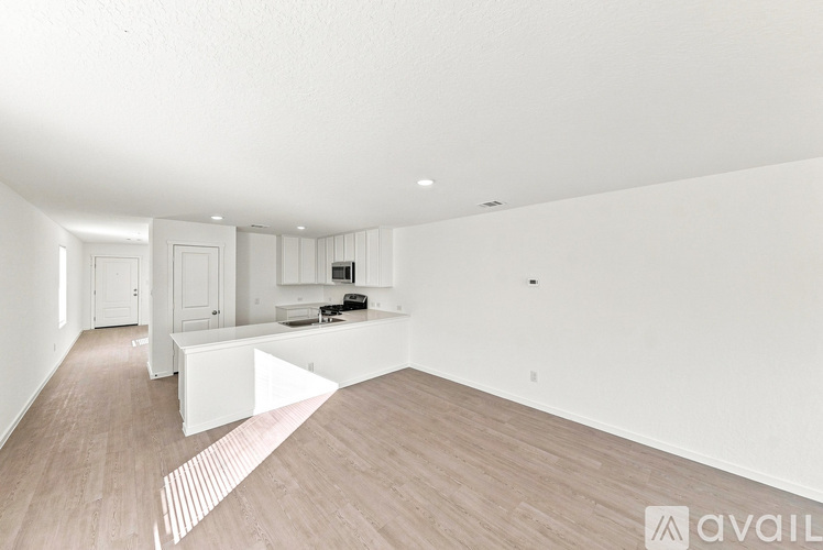 A spacious, empty room with wooden flooring and white walls.