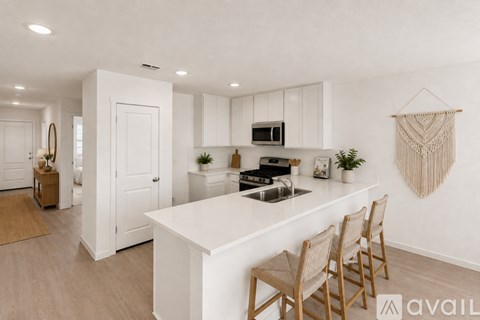 A kitchen with white cabinets and a white island with three chairs.
