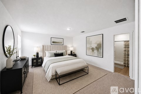 A bedroom with a large bed, a mirror, and a painting on the wall.