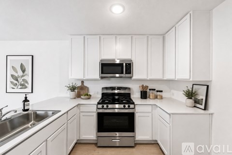 A modern kitchen with white cabinets and stainless steel appliances.