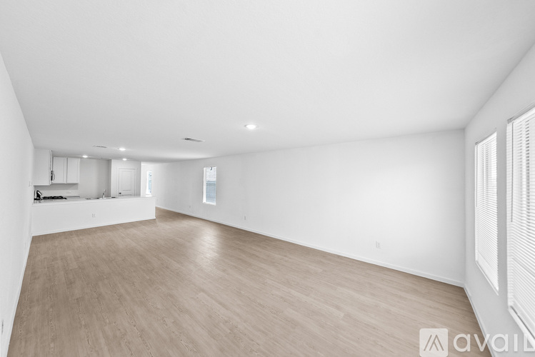 A spacious room with wooden flooring and white walls.