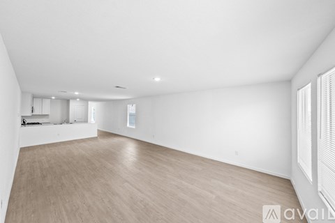 A spacious room with wooden flooring and white walls.