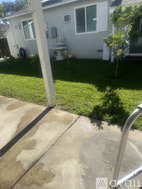 A white house with a green lawn and a grey concrete walkway.