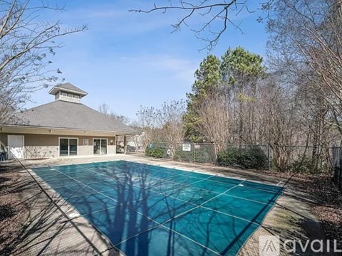 A pool surrounded by trees and a building with a cupola.