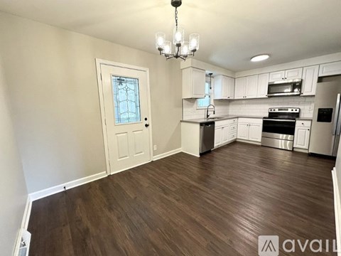 A kitchen with white cabinets and a wooden floor.