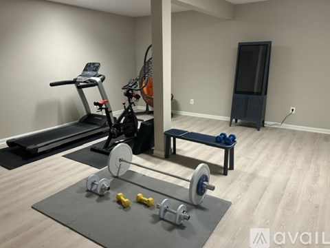 A home gym with a treadmill, bench, and weights.