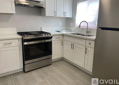 A modern kitchen with white cabinets and a stainless steel refrigerator.