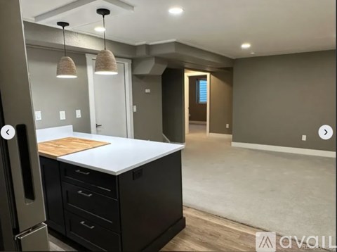 A kitchen with a black counter and a wooden cutting board.