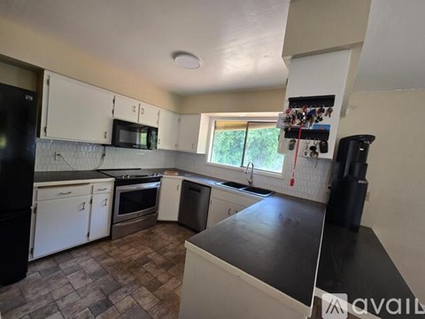 A kitchen with black appliances and white cabinets.