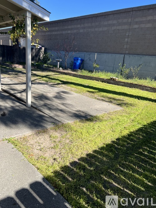A grassy area with a sidewalk and a pole in the foreground.