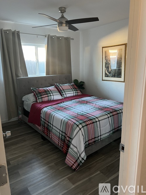 A bedroom with a bed, a ceiling fan, and a window with curtains.
