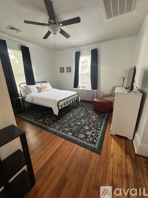 A bedroom with a bed, a dresser, and a ceiling fan.