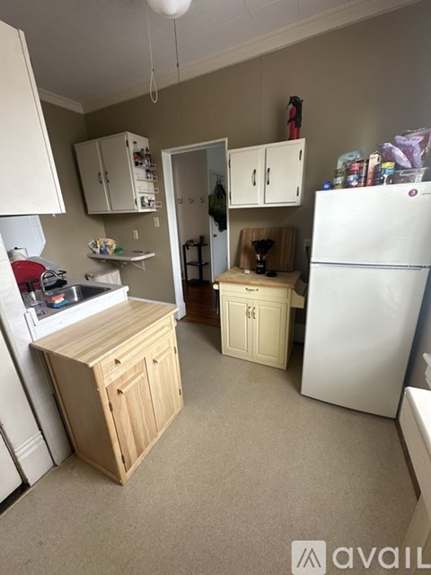 A kitchen with a white refrigerator, wooden cabinets, and a white stove top.