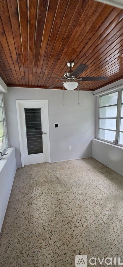 A room with a wooden ceiling and a fan.