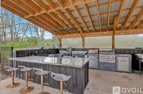 A wooden outdoor kitchen with a grill and sink.