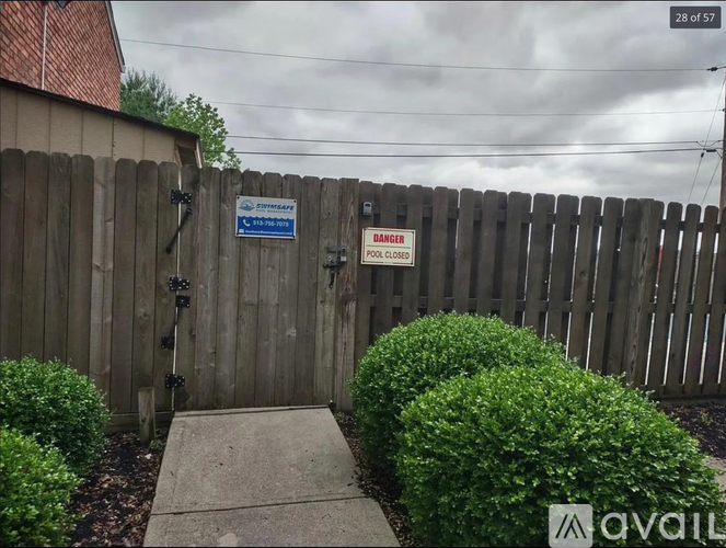A wooden fence with a sign that says "DANGER POOL CLOSED" is in front of a house.