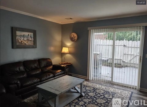 A living room with a black leather couch and a wooden coffee table.