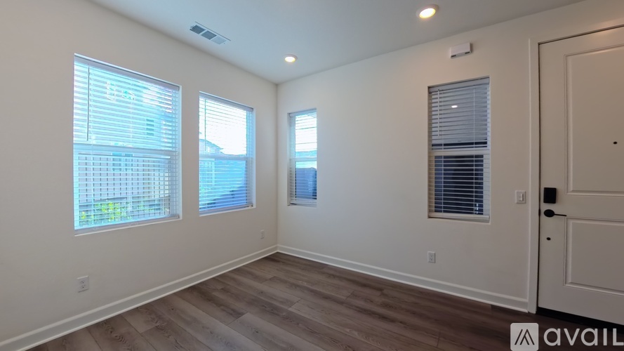 A room with wooden flooring and three windows.