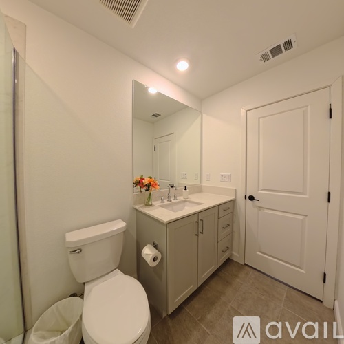 A bathroom with a toilet, sink, and mirror.