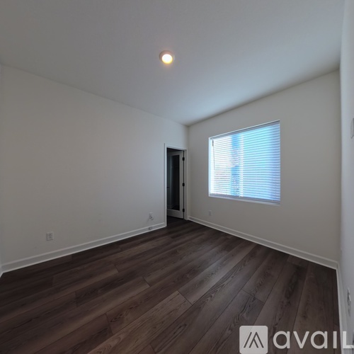 A room with wooden flooring and a window with blinds.