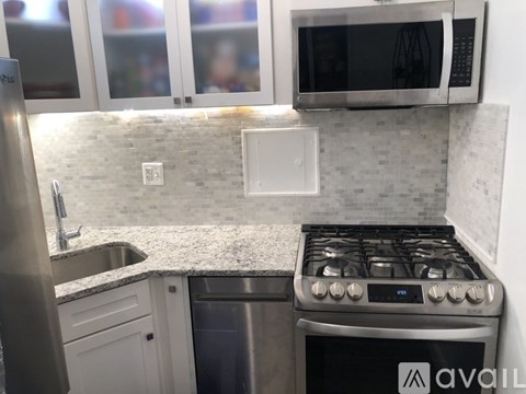 A kitchen with a stove, sink, and microwave.