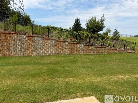 A grassy field with a brick wall and a metal fence.