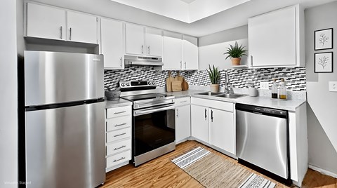 A modern kitchen with a stainless steel refrigerator and white cabinets.