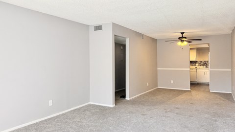 A spacious room with a ceiling fan and a doorway leading to another room.