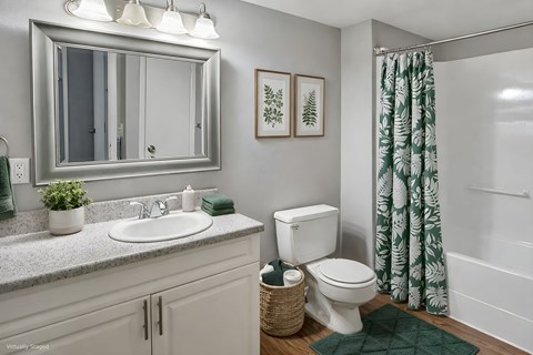 A bathroom with a white toilet, sink, and green shower curtain.