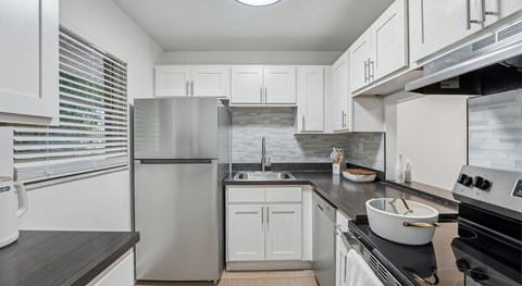 A modern kitchen with white cabinets and stainless steel appliances.