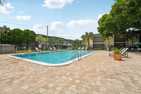 A pool surrounded by a brick patio.