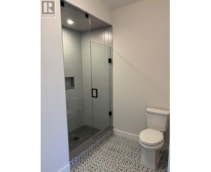 A white toilet in a bathroom with a glass shower stall.