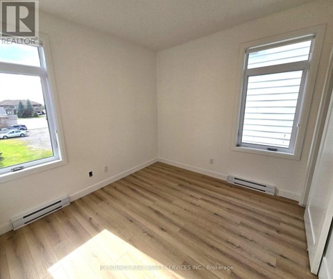 A room with wooden flooring and a window with blinds.