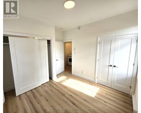 A room with white walls and wooden flooring, with a laundry basket in the corner.