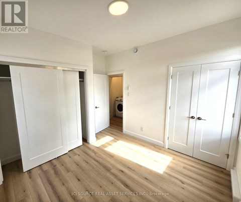 A room with white walls and wooden flooring, with a laundry basket in the corner.