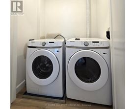 Two white front load washing machines in a laundry room.