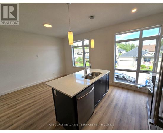 A kitchen with a sink and a window overlooking a parking lot.