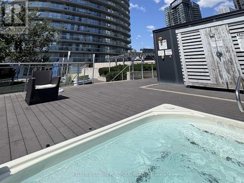 A hot tub on a wooden deck with a cityscape in the background.