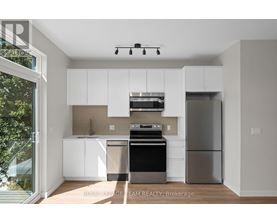 A modern kitchen with white cabinets and stainless steel appliances.