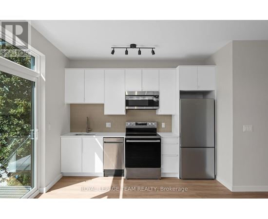 A modern kitchen with white cabinets and stainless steel appliances.
