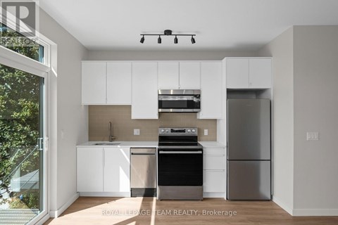 A modern kitchen with white cabinets and stainless steel appliances.